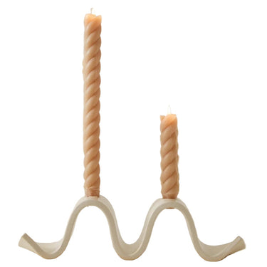 Wavy candle holder with two twisted candles on a plain background