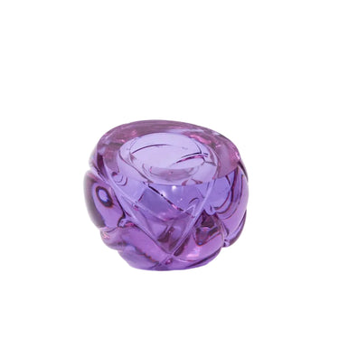 A small, translucent purple glass sculpture with a faceted, organic shape, photographed on a seamless white background.