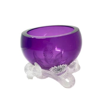 A purple glass bowl with a clear glass pedestal base, featuring etched floral details on the base and rim, set against a plain white background.